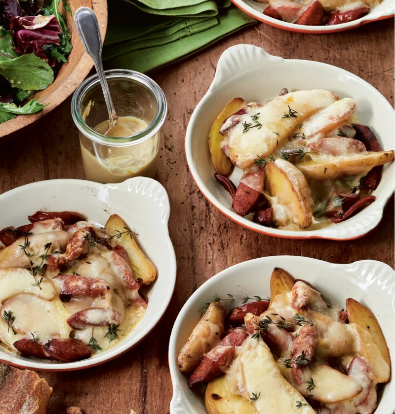 Baked raclette gratin with chorizo, fingerling potatoes, and melted cheese in a dish