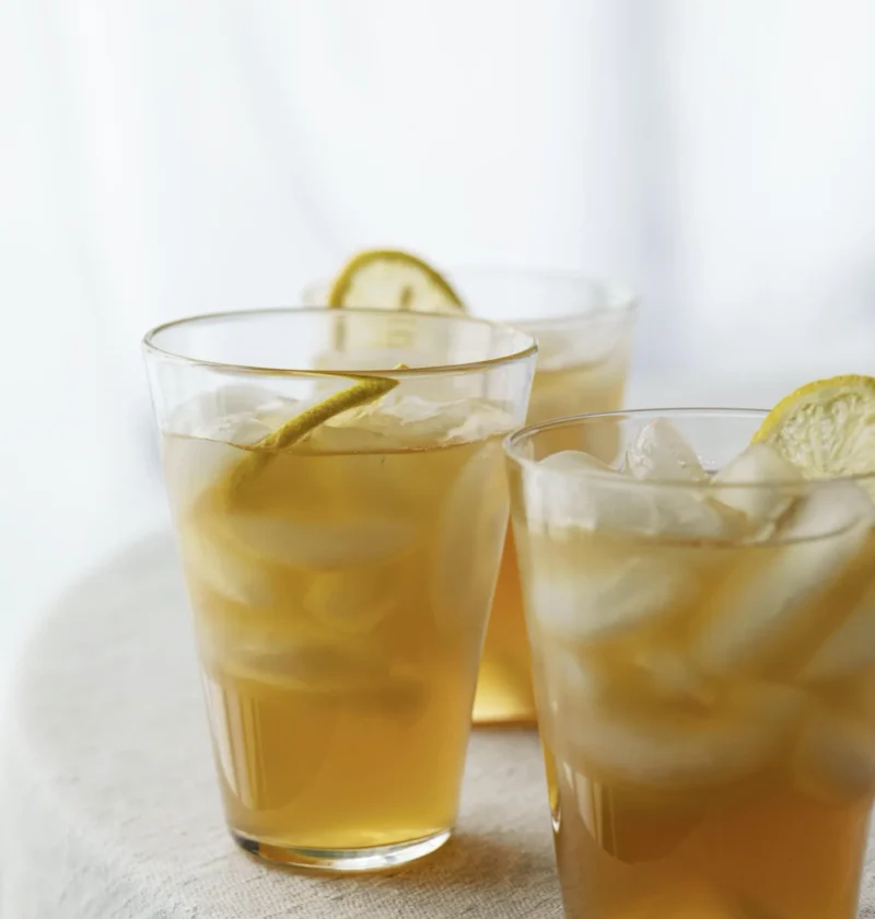 Three glasses of ina garten bourbon arnold palmers over ice with lemon slices on a linen cloth
