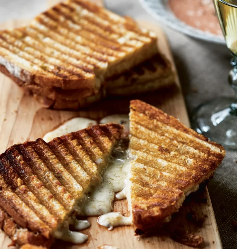 Cheddar and chutney grilled cheese sandwiches cut in half diagonally showing melted sharp white Cheddar and mango chutney on golden pressed bread