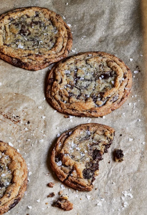 Giant crinkled chocolate chip cookies with bittersweet chocolate chunks and fleur de sel on a baking sheet