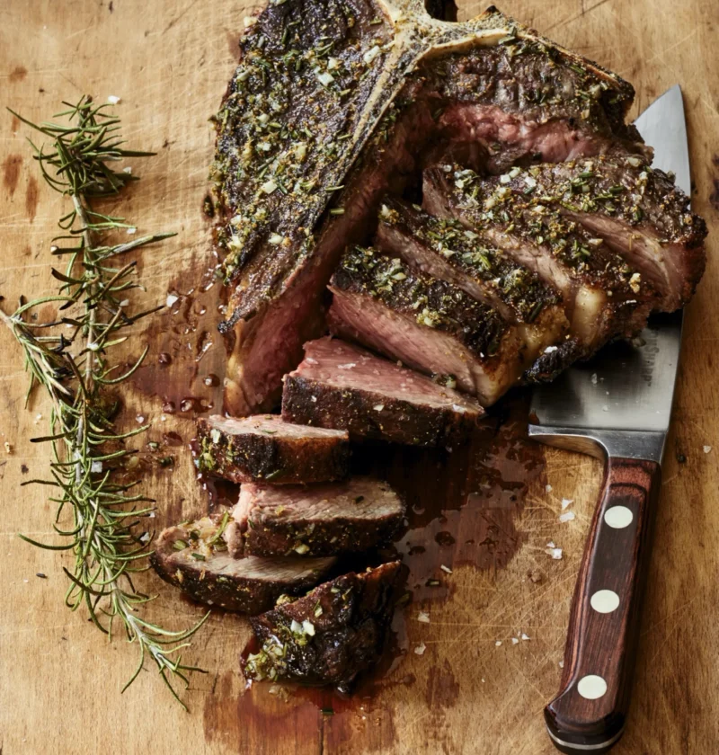 Grilled porterhouse steak sliced on a plate with rosemary and fennel herb oil, a dinner party recipe from Ina Garten