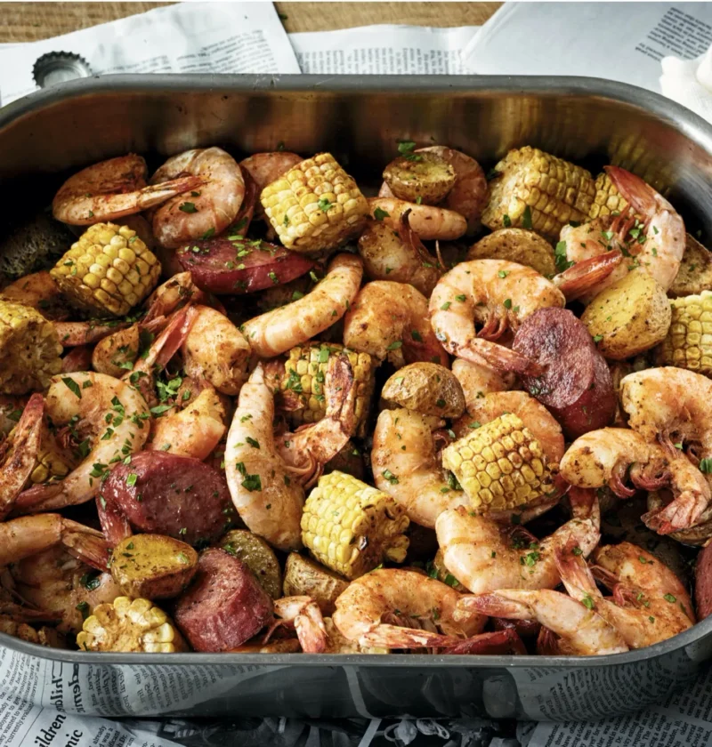 Ina Garten oven-roasted southern shrimp boil on a roasting pan with shrimp, corn, potatoes, and kielbasa seasoned with Old Bay