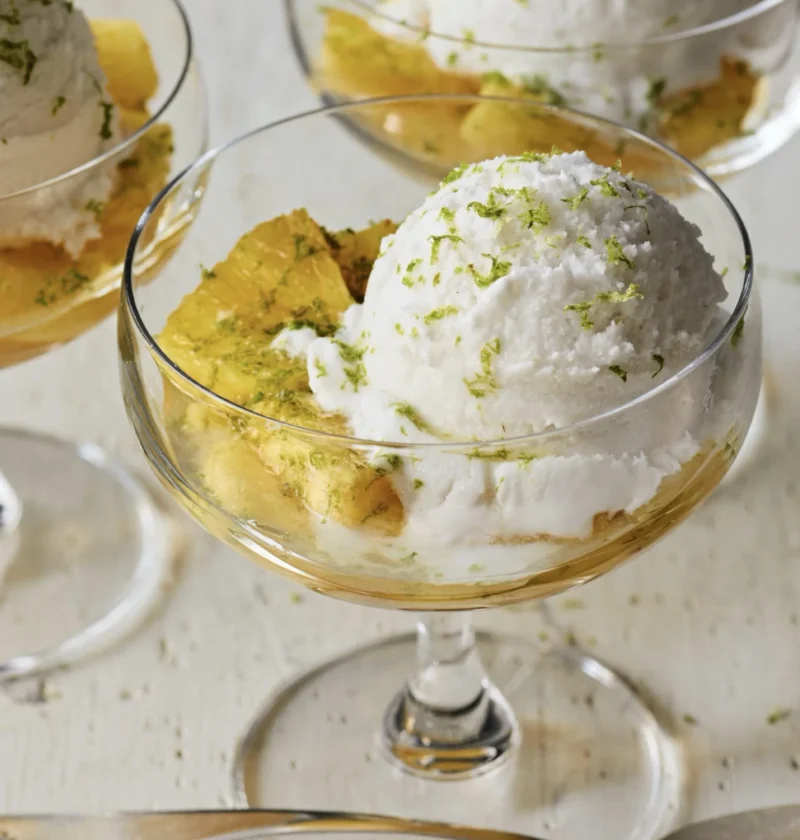 Roasted golden pineapple pieces topped with coconut gelato and lime zest in a dessert bowl, Ina Garten roasted pineapple with coconut gelato recipe