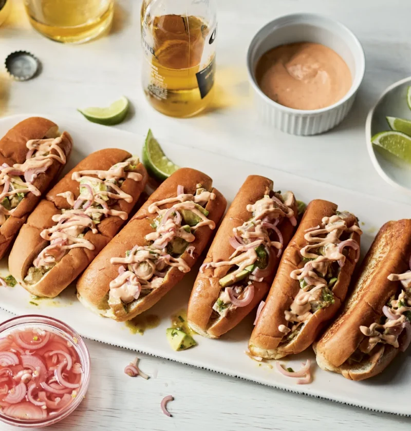Ina Garten seared tuna & avocado rolls on a white platter, drizzled with chipotle mayonnaise and topped with pickled shallots
