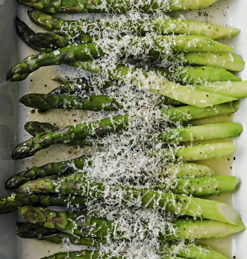 Thick asparagus spears roasted with melted Pecorino and Parmesan cheese in a white baking dish, Ina Garten asparagus cacio e pepe