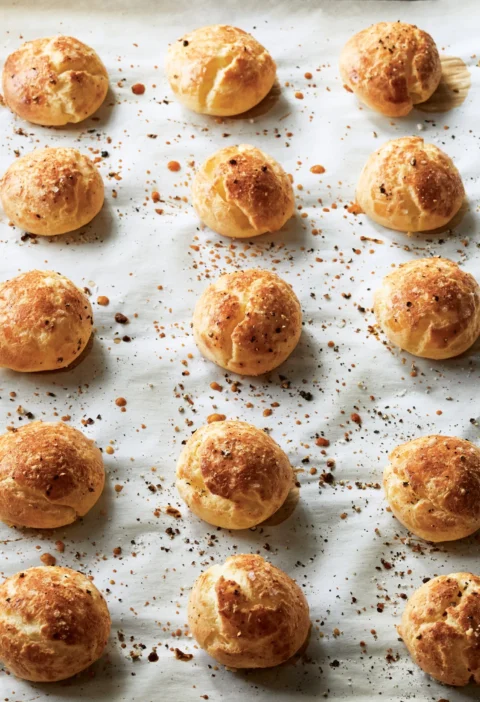 Ina Garten cacio e pepe cheese puffs on a platter, golden brown with Pecorino cheese and black pepper