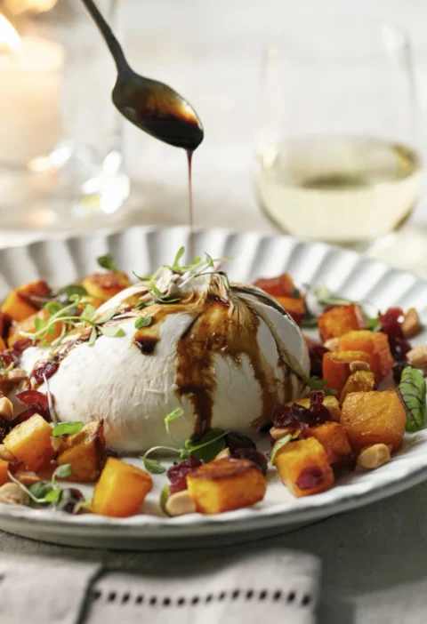 Caramelized butternut squash with burrata, Marsala cranberries and Marcona almonds on a dinner plate