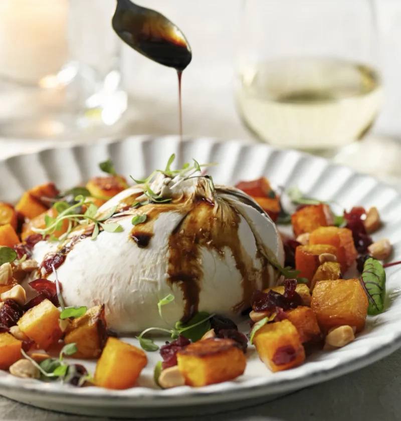 Caramelized butternut squash with burrata, Marsala cranberries and Marcona almonds on a dinner plate