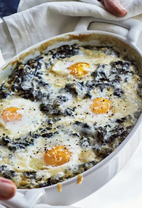 Ina Garten creamed spinach and eggs baked in a dish with melted Gruyère cheese on top