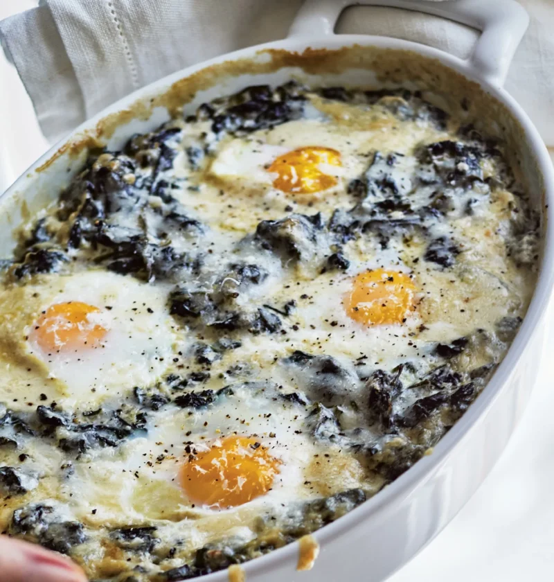 Ina Garten creamed spinach and eggs baked in a dish with melted Gruyère cheese on top