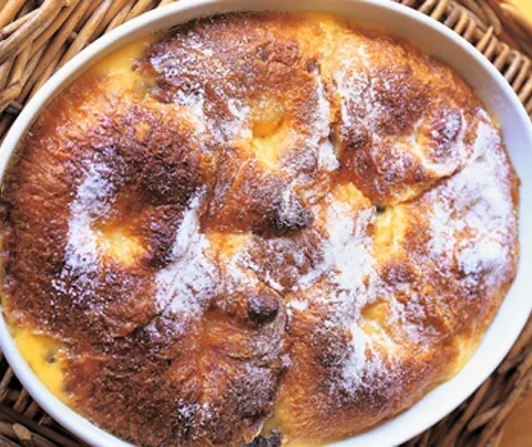 Ina Garten croissant bread pudding in an oval baking dish with golden puffed top and visible layers of croissants and custard