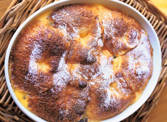 Ina Garten croissant bread pudding in an oval baking dish with golden puffed top and visible layers of croissants and custard