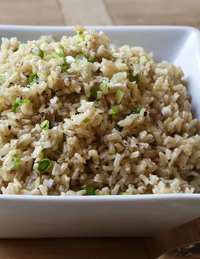 A bowl of gingered basmati rice with visible scallions and herbs, a flavorful ina garten side dish
