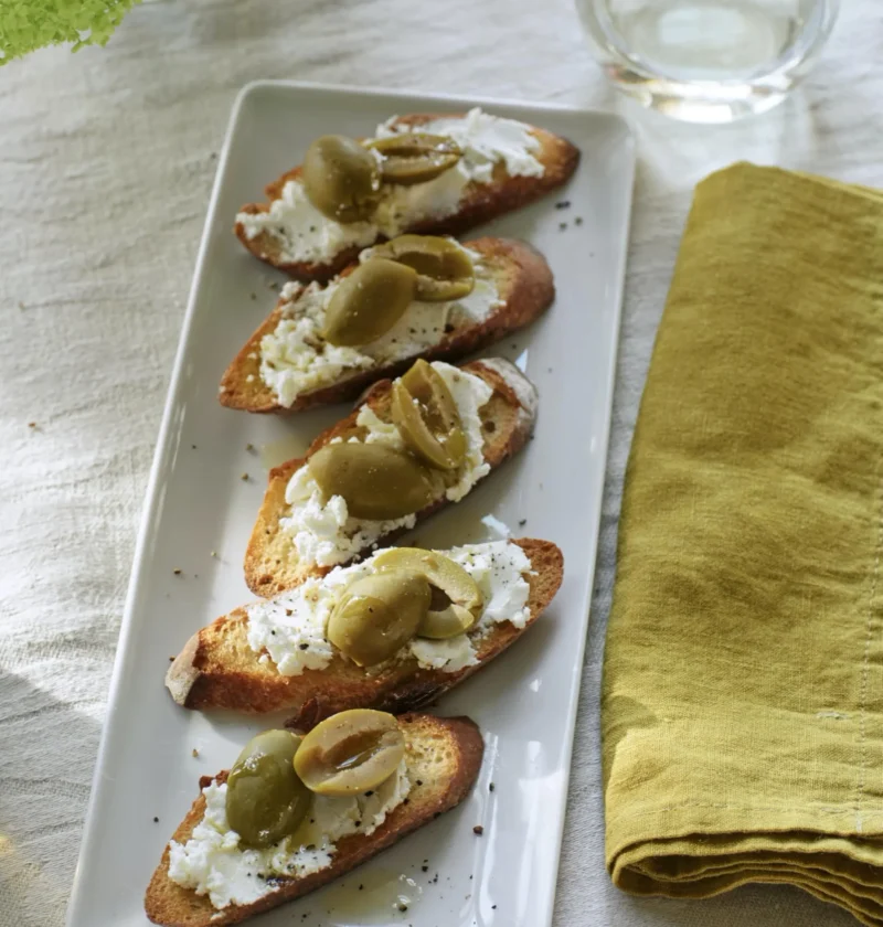 Ina Garten goat cheese toasts with Castelvetrano olives on a serving board
