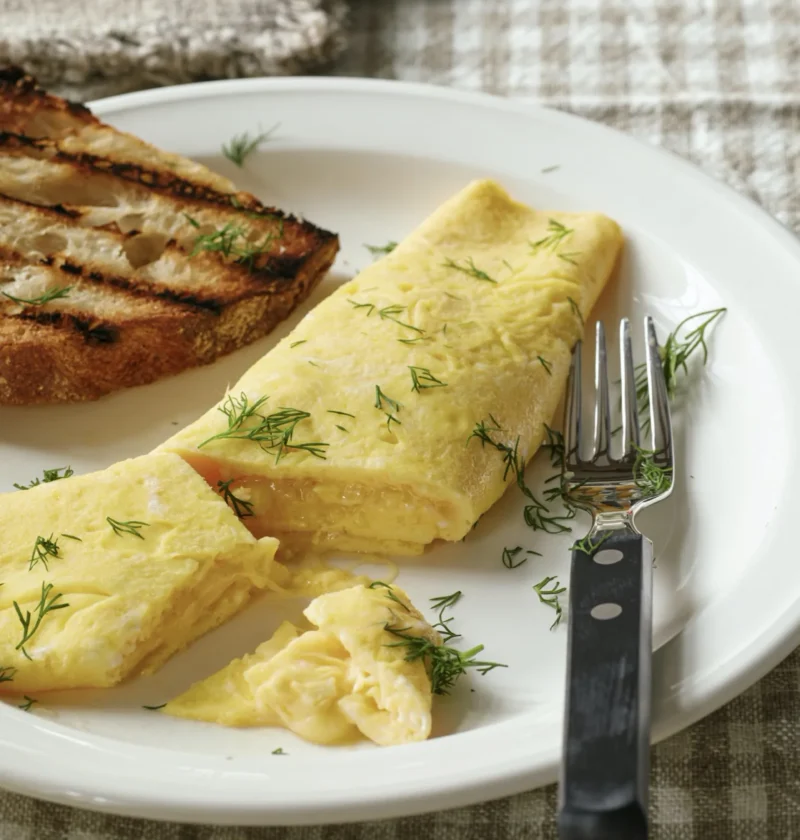 Ina Garten gruyère omelet with melted cheese folded inside golden eggs on a white plate