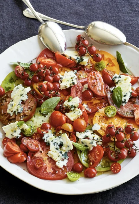 Ina Garten heirloom tomato and blue cheese salad with ripe sliced tomatoes, crumbled Roquefort, and fresh basil on a platter