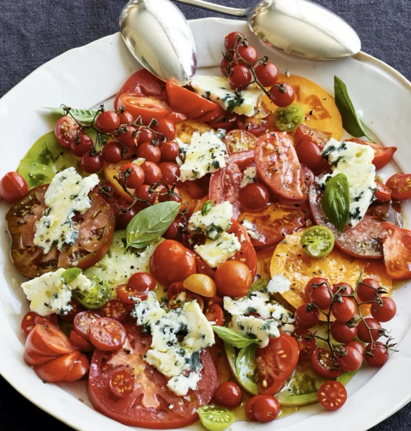 Ina Garten heirloom tomato and blue cheese salad with ripe sliced tomatoes, crumbled Roquefort, and fresh basil on a platter