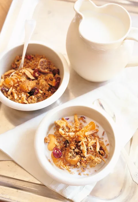 A bowl of Ina Garten homemade granola with toasted oats, coconut, almonds, dried fruits, and cashews