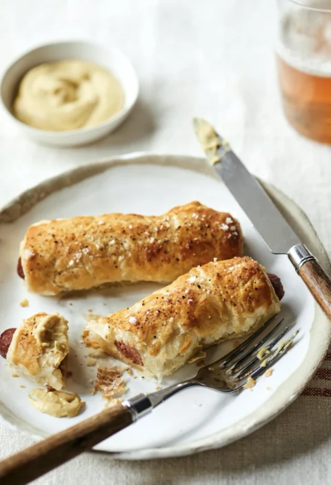 Golden puff pastry wrapped hot dogs sprinkled with flaked sea salt on a sheet pan, Ina Garten hot dogs in puff pastry