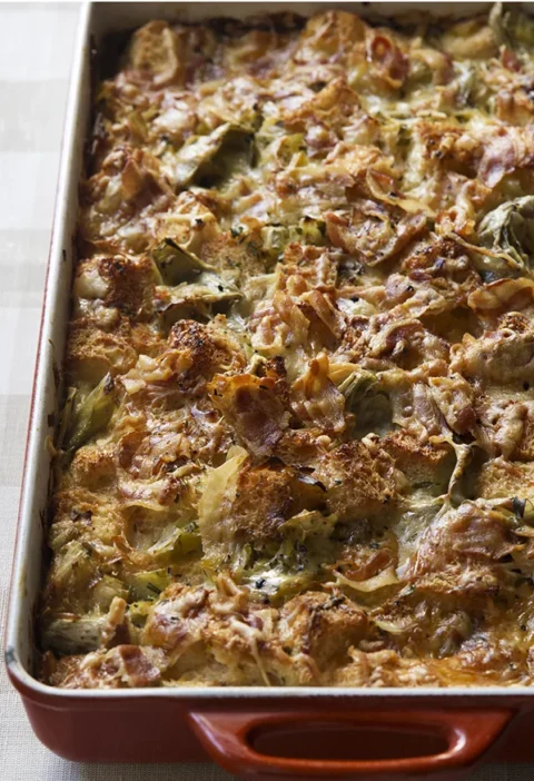 Ina Garten leek and artichoke bread pudding in a baking dish with golden cheese on top