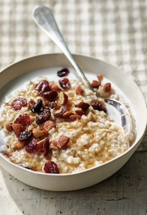 A bowl of creamy overnight Irish oatmeal topped with chopped nuts and dried cranberries, an easy Ina Garten overnight Irish oatmeal recipe
