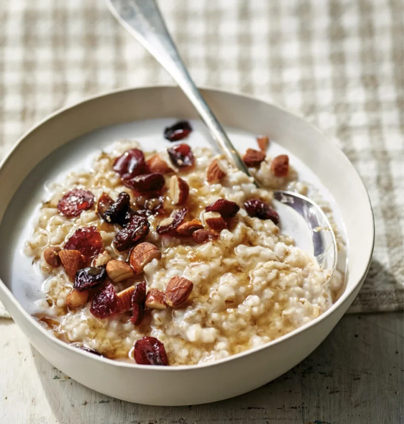 A bowl of creamy overnight Irish oatmeal topped with chopped nuts and dried cranberries, an easy Ina Garten overnight Irish oatmeal recipe