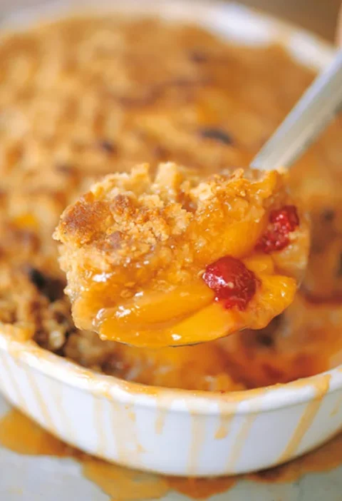 Ina Garten peach and raspberry crisp with golden oatmeal crumble topping in an oval baking dish