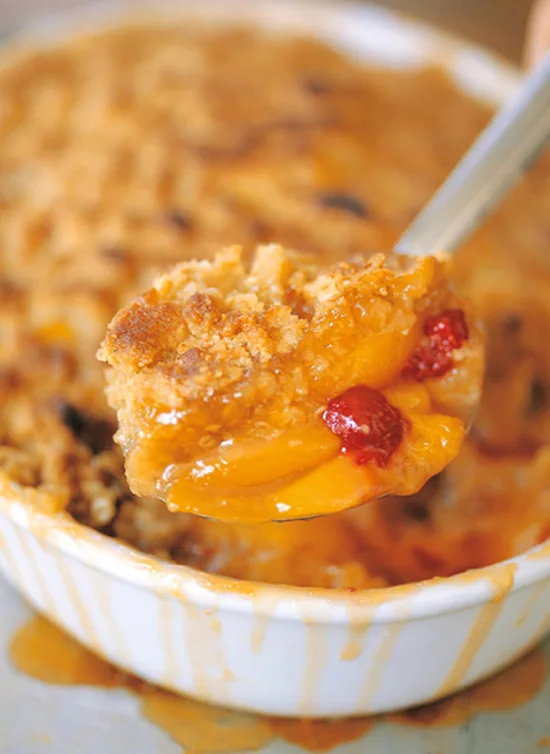 Ina Garten peach and raspberry crisp with golden oatmeal crumble topping in an oval baking dish