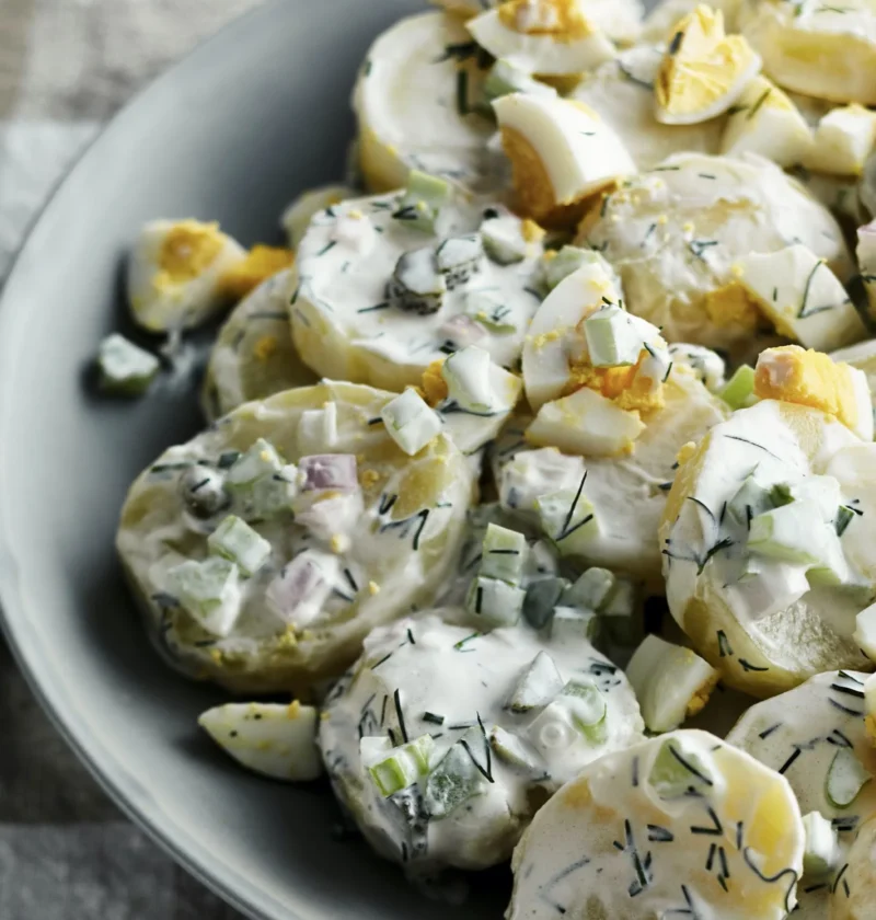 A bowl of creamy ina garten potato salad à la julia child with Yukon Gold potatoes, fresh dill, cornichons, and hard-boiled eggs