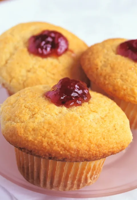 Ina Garten raspberry corn muffins with golden crisp tops and raspberry preserves piped into the center