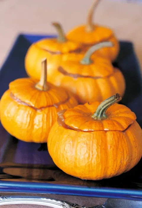 Roasted baby pumpkins filled with applesauce on a baking sheet, a festive fall side dish from Ina Garten
