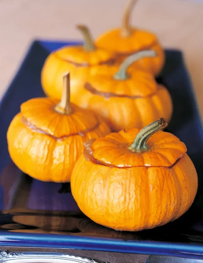 Roasted baby pumpkins filled with applesauce on a baking sheet, a festive fall side dish from Ina Garten