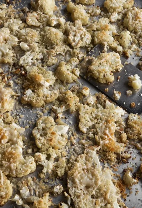 Roasted cauliflower slices topped with crispy panko and Parmesan cheese on a sheet pan, Ina Garten roasted cauliflower snowflakes recipe