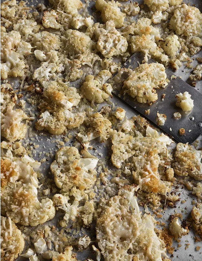 Roasted cauliflower slices topped with crispy panko and Parmesan cheese on a sheet pan, Ina Garten roasted cauliflower snowflakes recipe