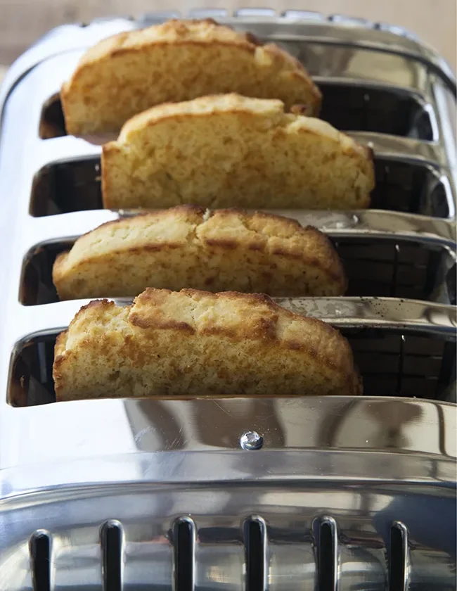 Two loaves of Ina Garten sour cream corn bread sliced and golden on a cutting board