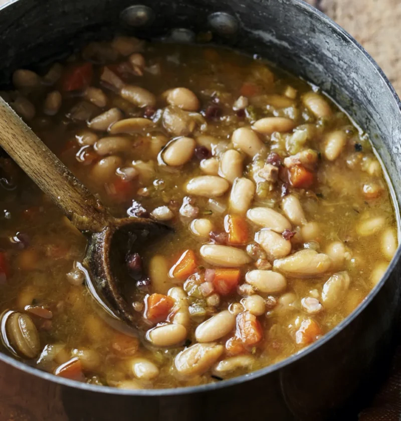 A bowl of tuscan white bean soup with pancetta, leeks, and rosemary topped with Parmesan cheese, a classic Ina Garten tuscan white bean soup recipe