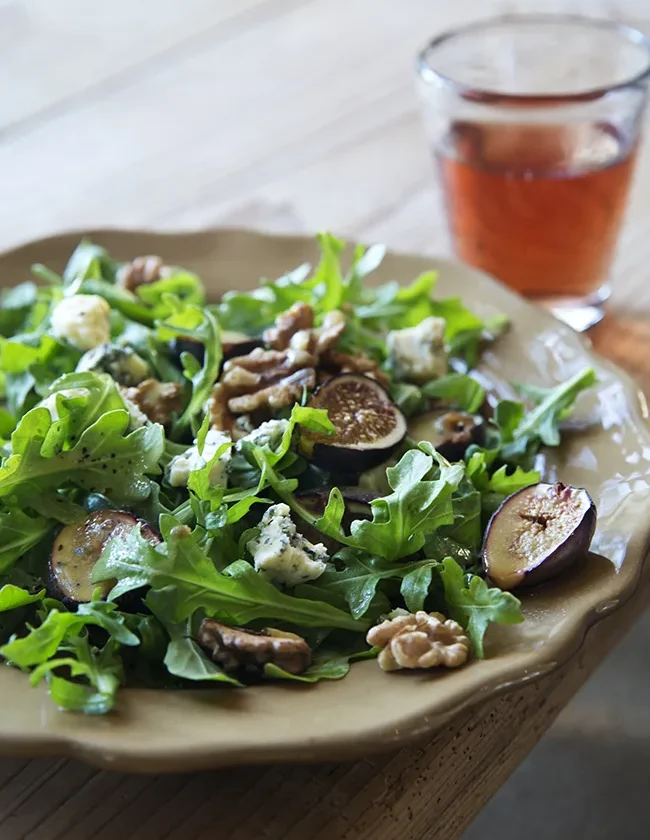 Warm fig and arugula salad with roasted figs, crumbled Roquefort cheese, and toasted walnuts on a bed of peppery arugula