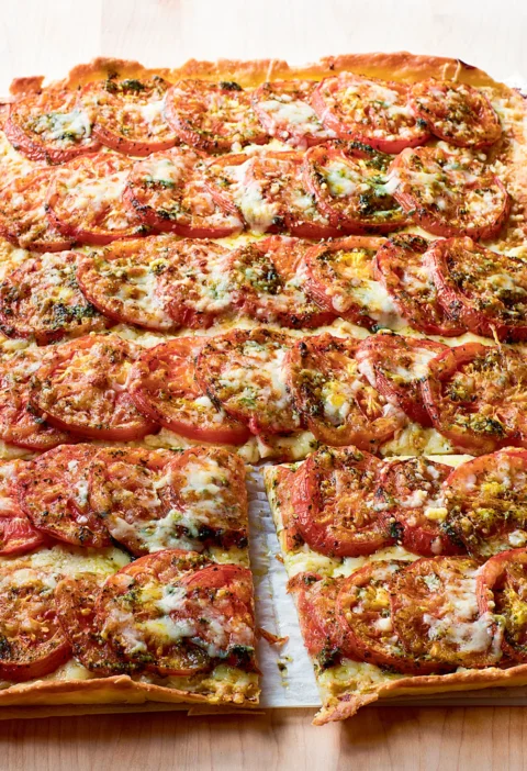 Ina Garten Anna's tomato tart with rows of overlapping sliced tomatoes, melted Gruyère and herbs on a golden crust