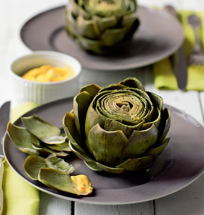 Ina Garten artichokes with lemon-tarragon aioli, whole cooked artichokes on gray plates with a small bowl of aioli