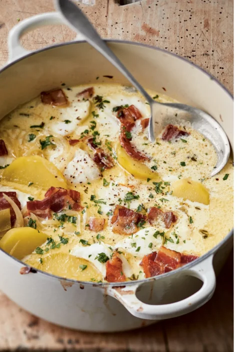 Ina Garten baked fish chowder in a white Dutch oven with cod, potatoes, crisp bacon and parsley