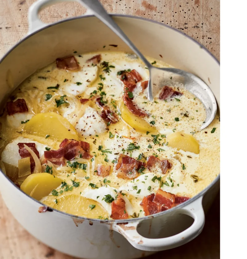 Ina Garten baked fish chowder in a white Dutch oven with cod, potatoes, crisp bacon and parsley