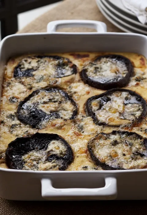 Ina Garten baked polenta with mushrooms and blue cheese with roasted portobello caps in a white baking dish
