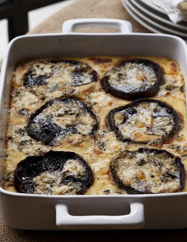 Ina Garten baked polenta with mushrooms and blue cheese with roasted portobello caps in a white baking dish