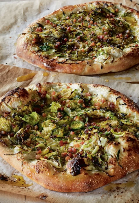 Ina Garten Brussels sprouts pizza carbonara with shaved sprouts, diced pancetta and melted cheese on parchment paper