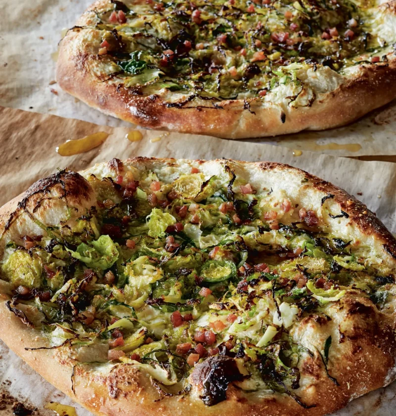 Ina Garten Brussels sprouts pizza carbonara with shaved sprouts, diced pancetta and melted cheese on parchment paper