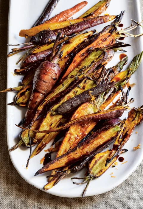 Ina Garten charred carrots, rainbow carrots broiled with thyme and drizzled with balsamic on a white oval platter