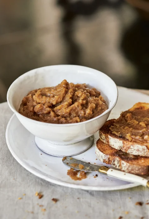 Ina Garten chunky apple butter in a white bowl next to toasted whole-grain bread spread with apple butter