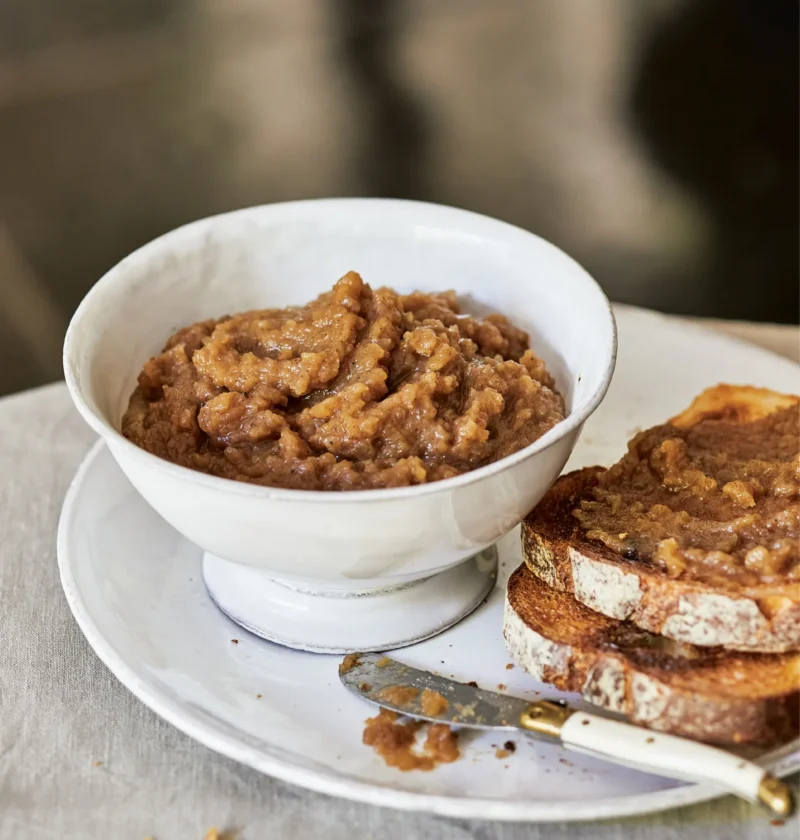 Ina Garten chunky apple butter in a white bowl next to toasted whole-grain bread spread with apple butter