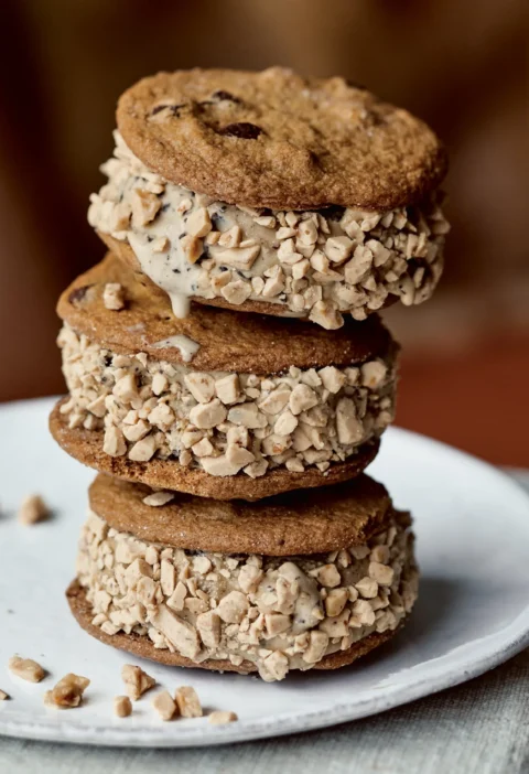 Stack of three Ina Garten coffee chocolate chip ice cream sandwiches rolled in toffee bits on a white plate