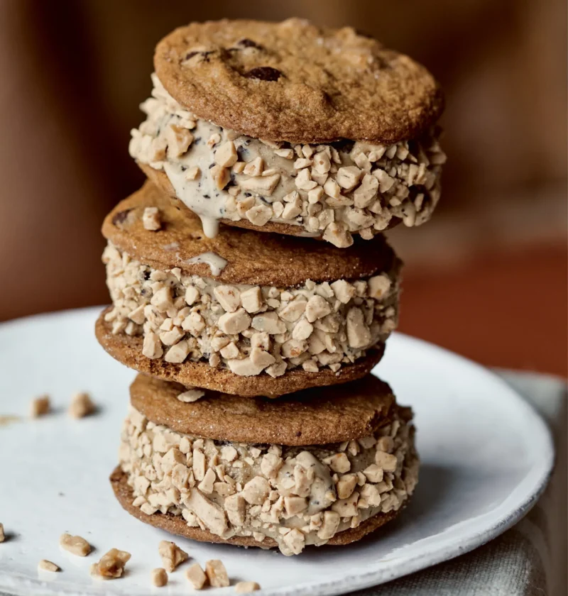 Stack of three Ina Garten coffee chocolate chip ice cream sandwiches rolled in toffee bits on a white plate
